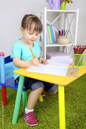 Little girl draws sitting a...