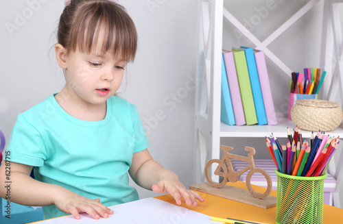 Little girl draws sitting a...