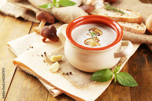 Mushroom soup in pot, on wooden background