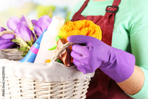 Fototapeta Naklejka Na Ścianę i Meble -  Housewife holding basket with cleaning equipment