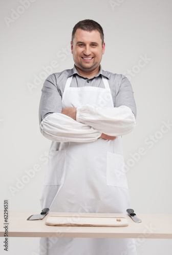 smiling butcher standing behind table.