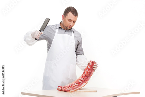 Canvas Print professional butcher cutting meat on table.