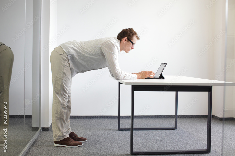 standing man typing at tablet in office, proper posture