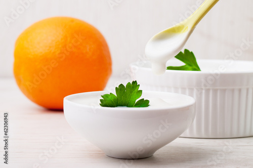 An orange and two white bowls with thick white yogurt