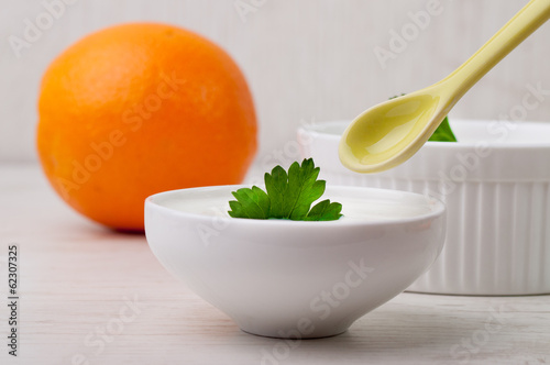 Two bowls with yogurt and an orange
