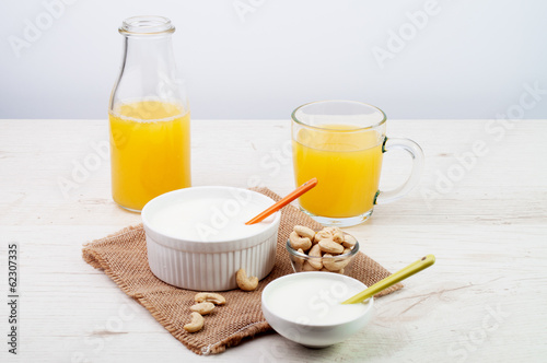 Yogurt with a bottle of juice and a bowl of nuts
