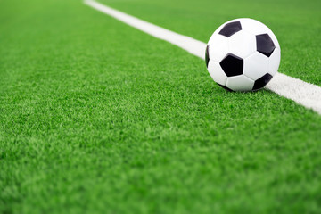 Traditional soccer ball on soccer field, green field sports background