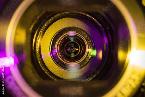 Video camera lens closeup lit by yellow and purple neon light photo