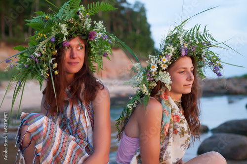 Two beautiful Girls with summer wreath of grass and flowers on t