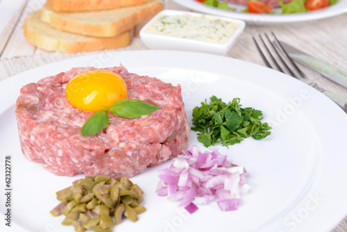 Delicious steak tartare with yolk on plate on table close-up