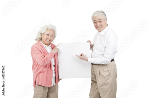 .Senior couple holding white board.
