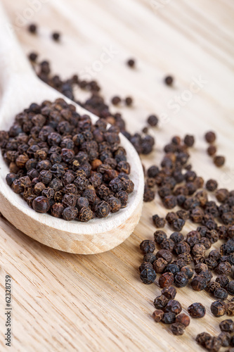 Black pepper on wooden spoon close up