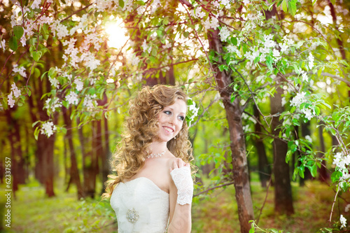 Beautiful bride in a white dress in blooming gardens