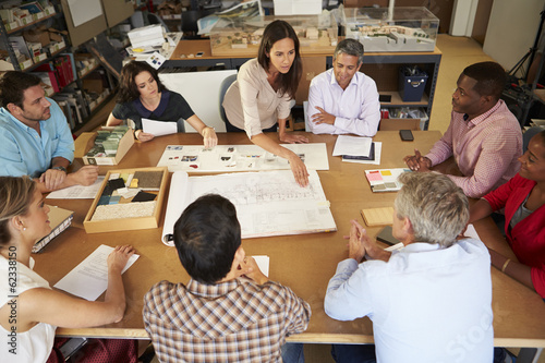 Female Boss Leading Meeting Of Architects Sitting At Table