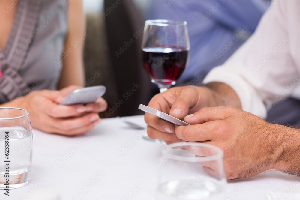Mid section of a couple with wine glass text messaging Mid section of a couple with wine glass text messaging