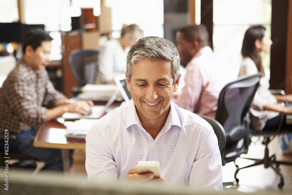 Businessman Working At Desk Using Mobile Phone