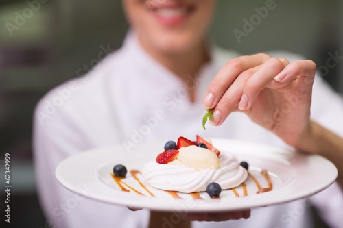 Happy chef putting mint leaf on dessert plate photo