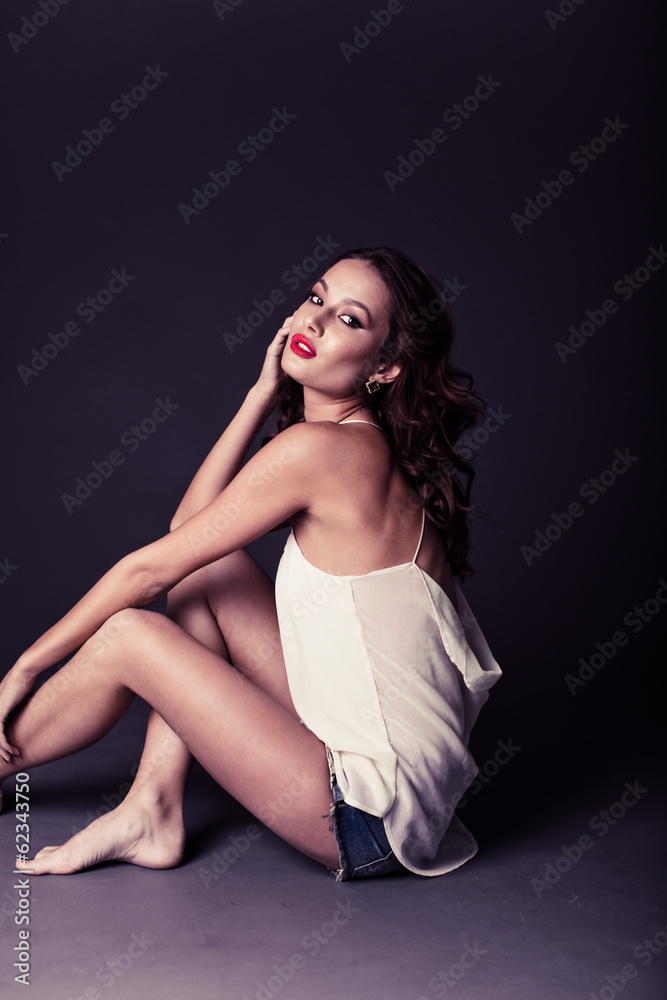 Sexy brunette sitting in a white T-shirt and shorts Sexy brunette sitting in a white T-shirt and shorts