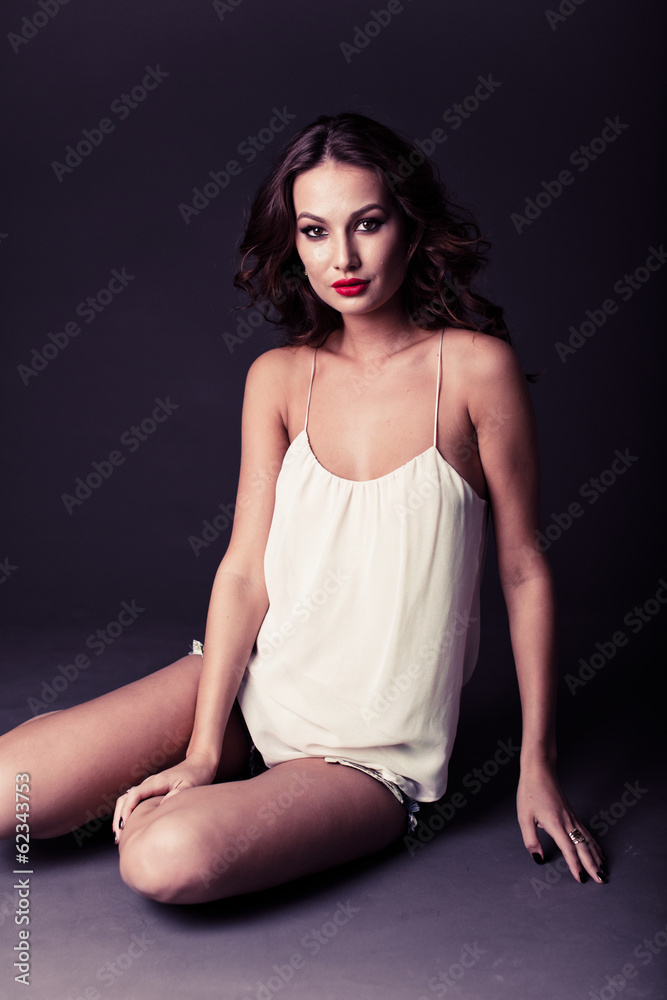 Sexy brunette sitting in a white T-shirt and shorts Sexy brunette sitting in a white T-shirt and shorts