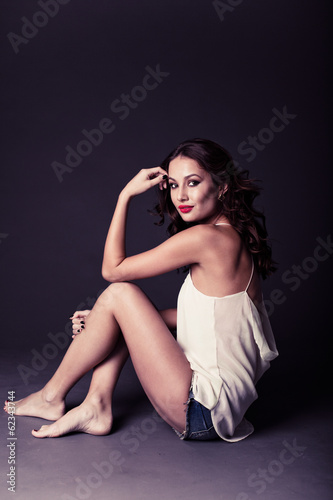 Sexy brunette sitting in a white T-shirt and shorts