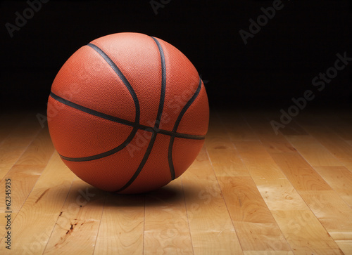 Basketball with dark background on a wood gym floor