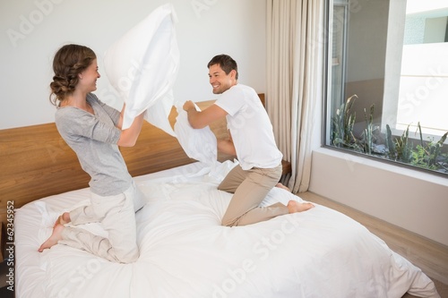 Happy couple having a pillow fight