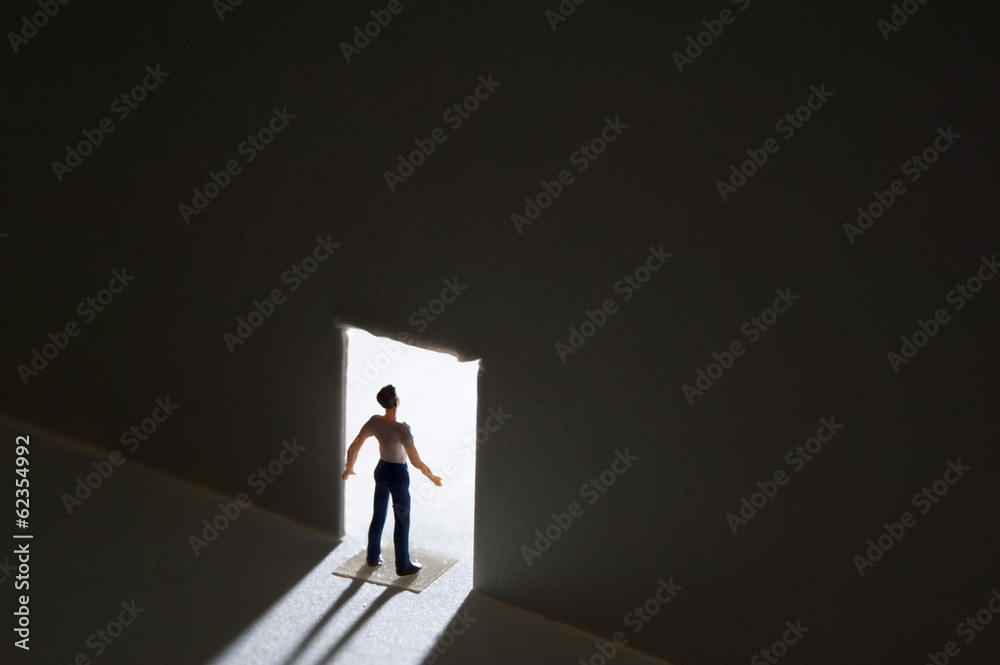 開いた扉から光を受ける男性