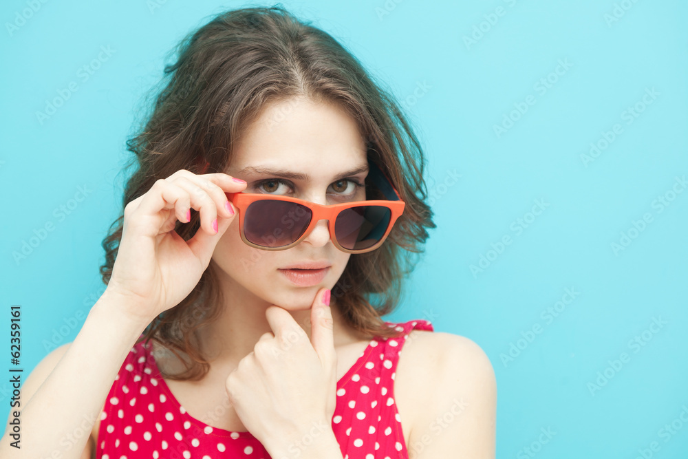 Fototapeta premium beautiful girl in sunglasses on a blue background in soft focus