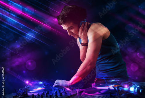 Young DJ playing on turntables with color light effects