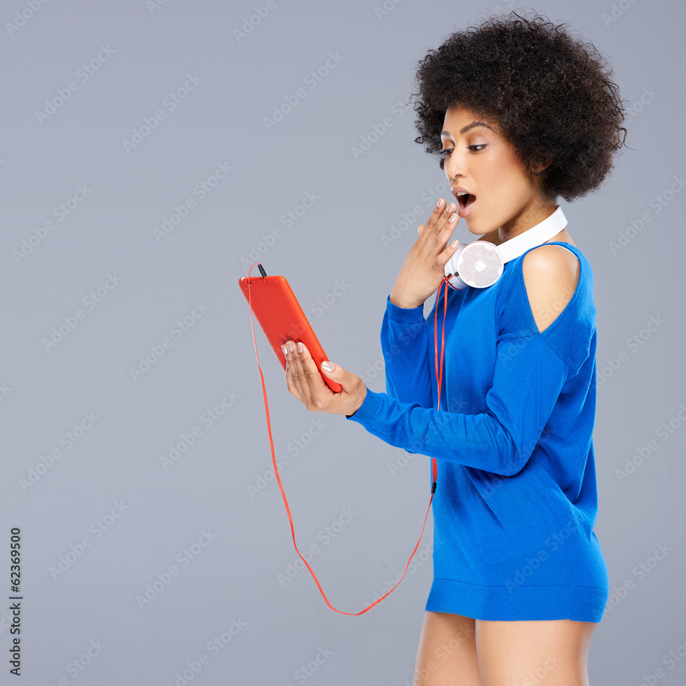 Shocked woman looking at her music storage device Shocked woman looking at her music storage device