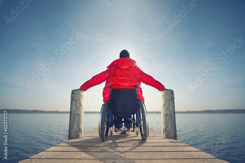 junger Mann im Rollstuhl am See photo