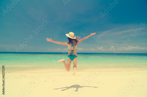 fun girl jumping holiday on a beach retro vintage effect