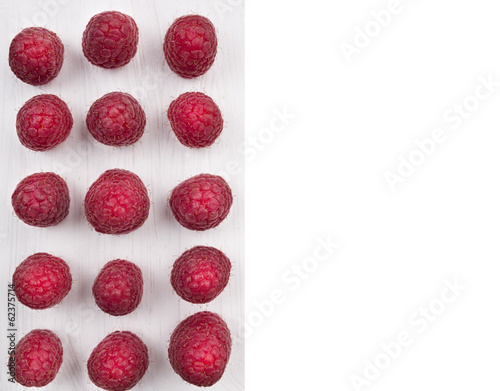 Raspberries laid out in row on white wooden board isolated