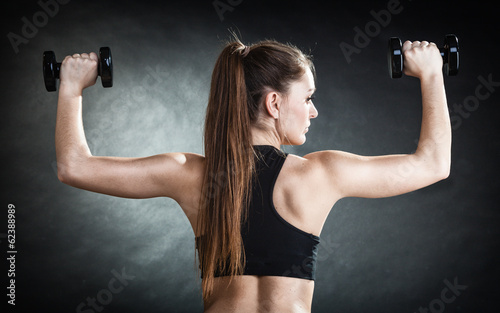 Fitness girl training shoulder muscles. Back view