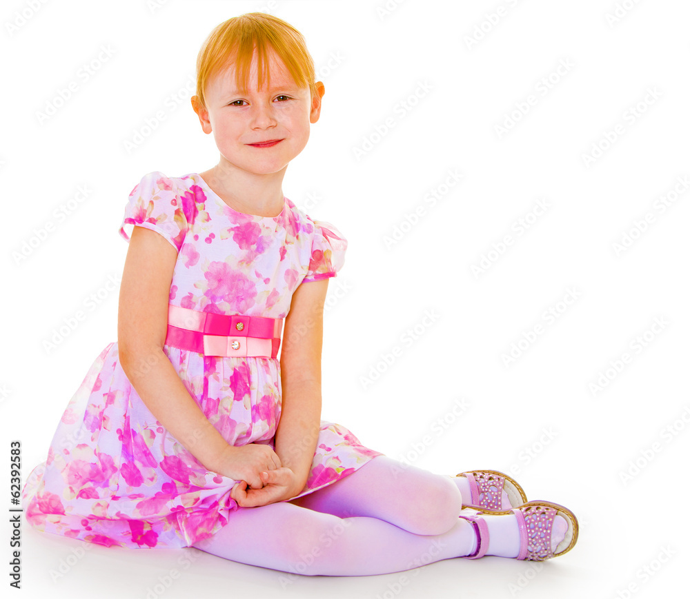 Sits leaning on hand a small charming girl.