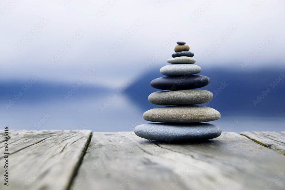 Zen Balancing Pebbles Next to a Misty Lake - obrazy, fototapety, plakaty 