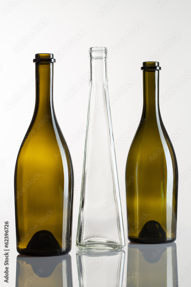 Three empty bottles of wine on a glass table