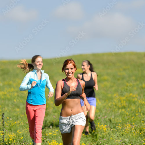 Friends enjoy running through sunny meadow