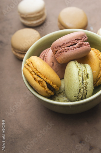 pastels macarons in bowl on old brown table