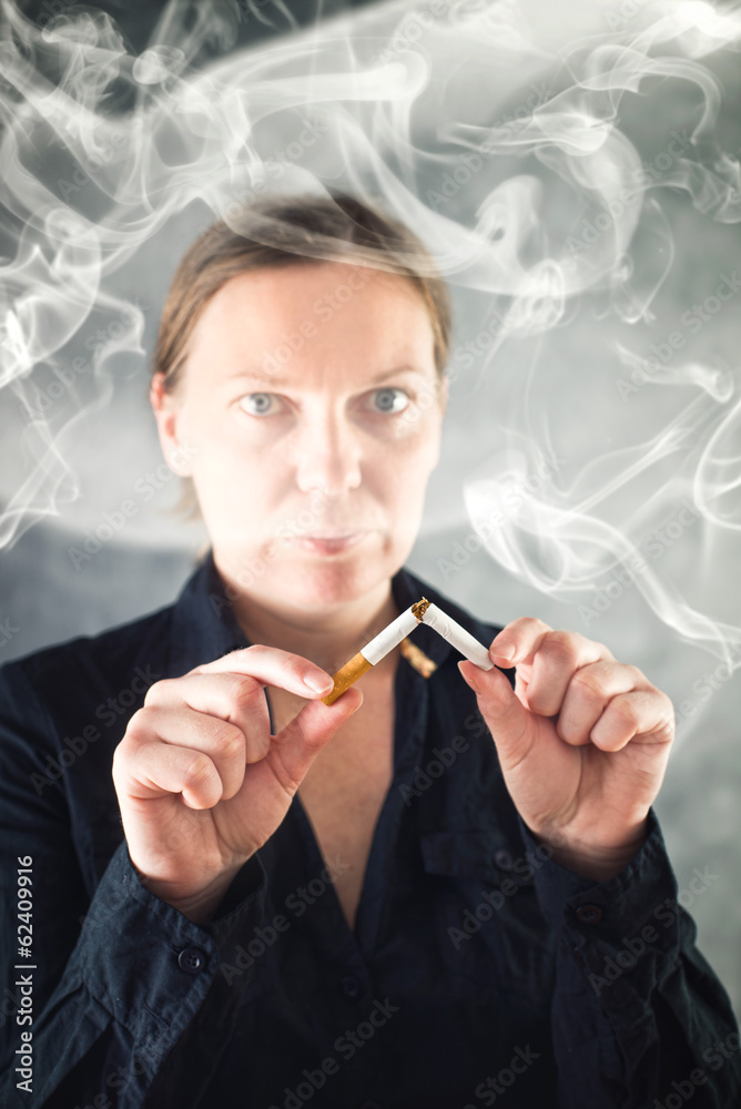Fototapeta premium Woman quits smoking and breaking cigarette in half