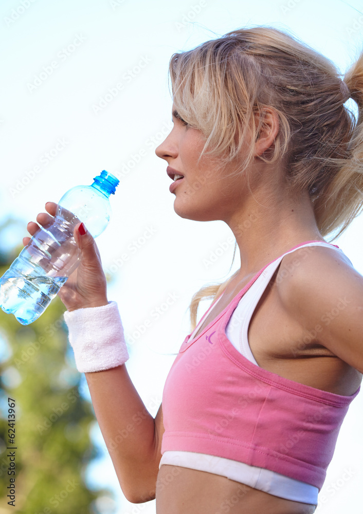 fitness and lifestyle concept - woman drinking water after doing fitness and lifestyle concept - woman drinking water after doing