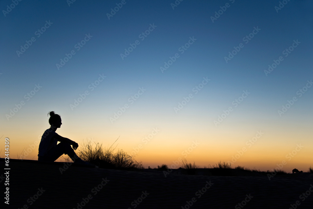 Silhouette de femme assise, soleil couchant