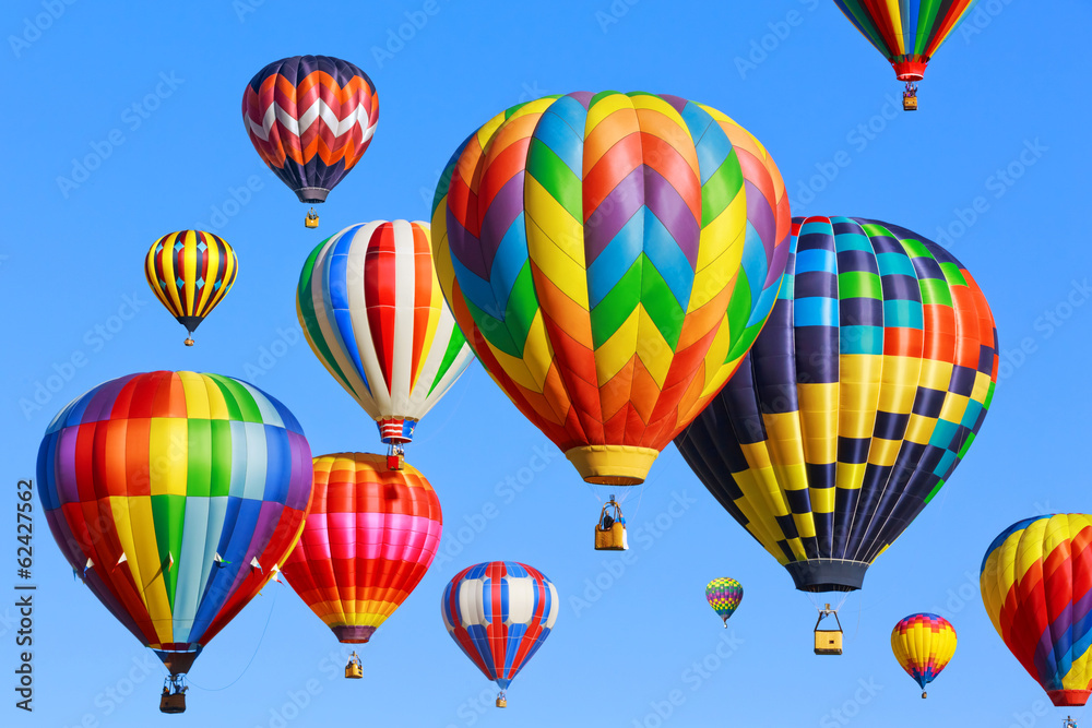 Fototapeta premium Colorful hot air balloons flying against clear blue sky, ballooning fiesta