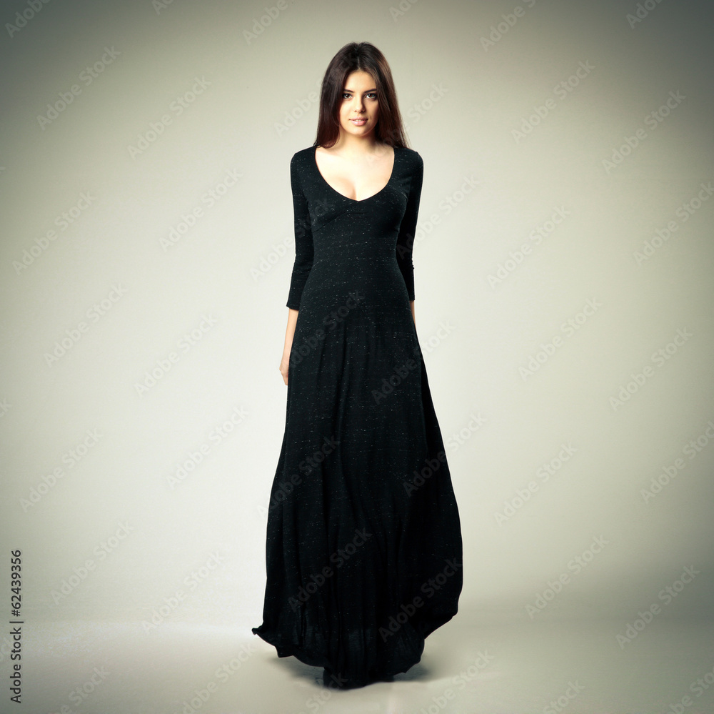 woman in long black dress on gray background woman in long black dress on gray background