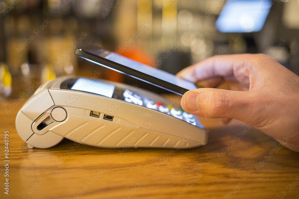 Man paying with NFC technology on mobile phone, restaurant, shop