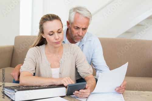 Принти на полотні Serious couple calculating their bills at the couch