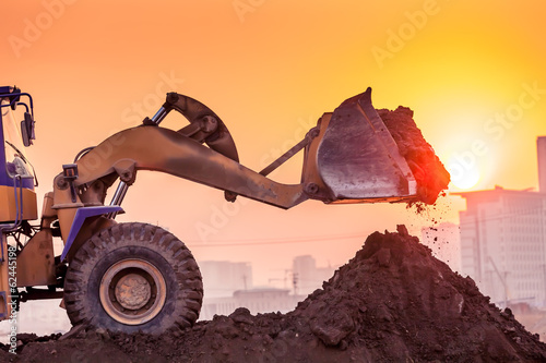 heavy wheel excavator machine working at sunset photo
