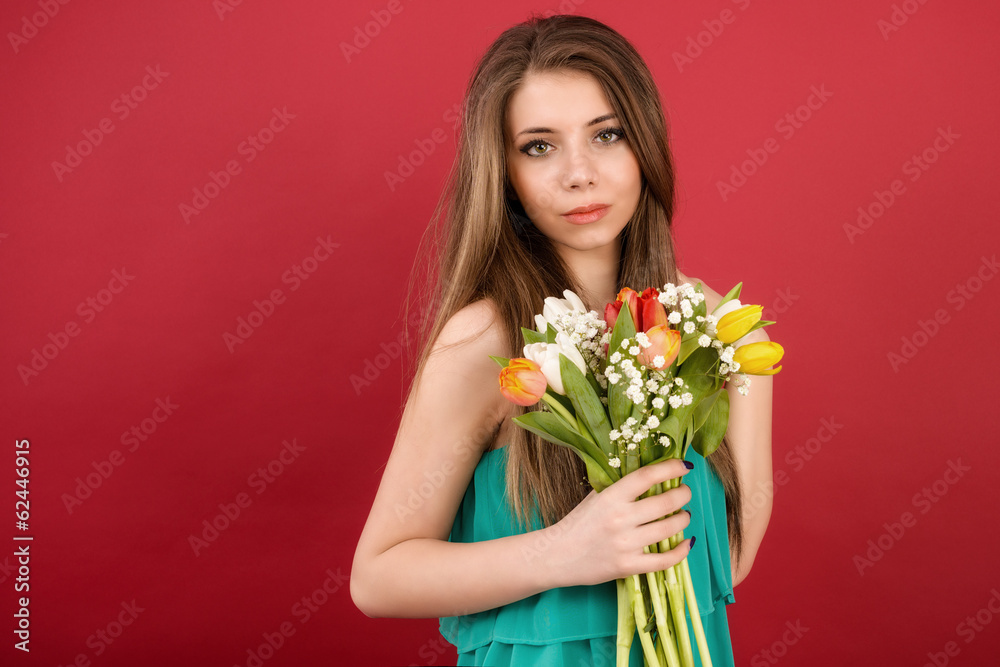 Beautiful girl in a summer dress with tulips on a red background Beautiful girl in a summer dress with tulips on a red background