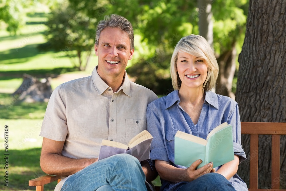 Couple reading books on bench in park Couple reading books on bench in park