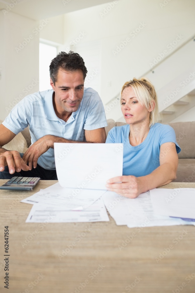 Concentrated couple with bills and calculator in living room Concentrated couple with bills and calculator in living room